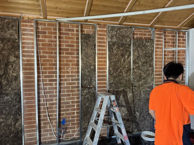 Brick wall opened up to studs with insulation batts fitted between them
