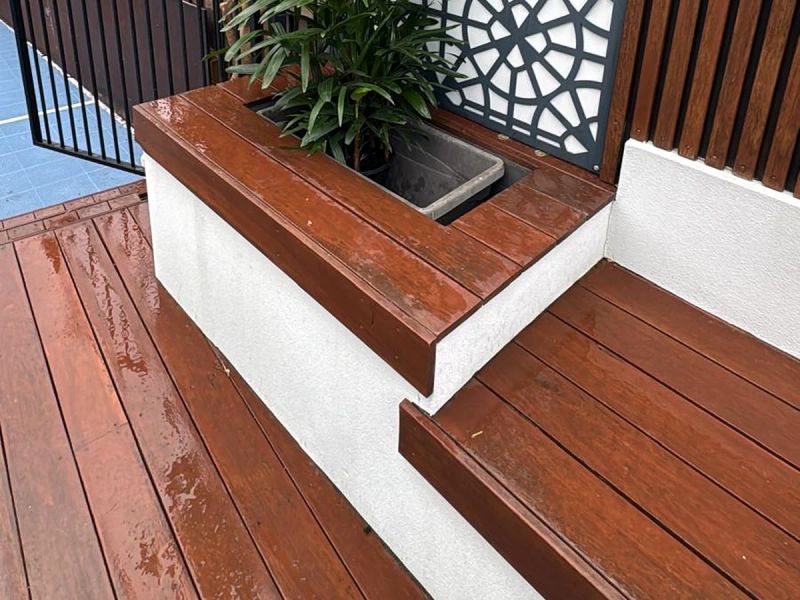 Oiled hardwood deck with a built-in planter box and bench seat beside a rendered wall