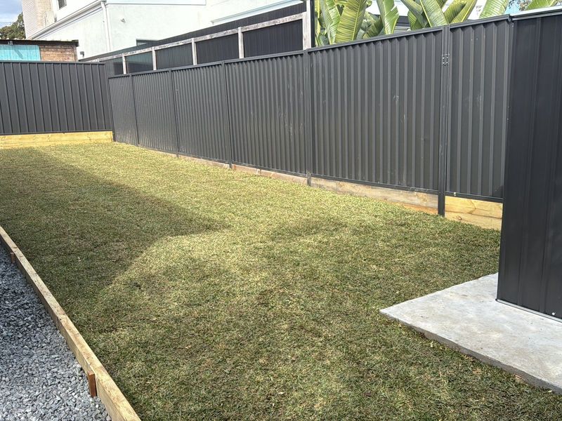 New charcoal Colorbond fence running the length of a turfed backyard