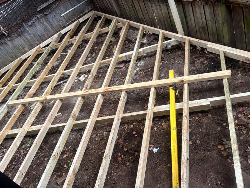 New treated pine joists laid across the bearers, with a spirit level checking the run