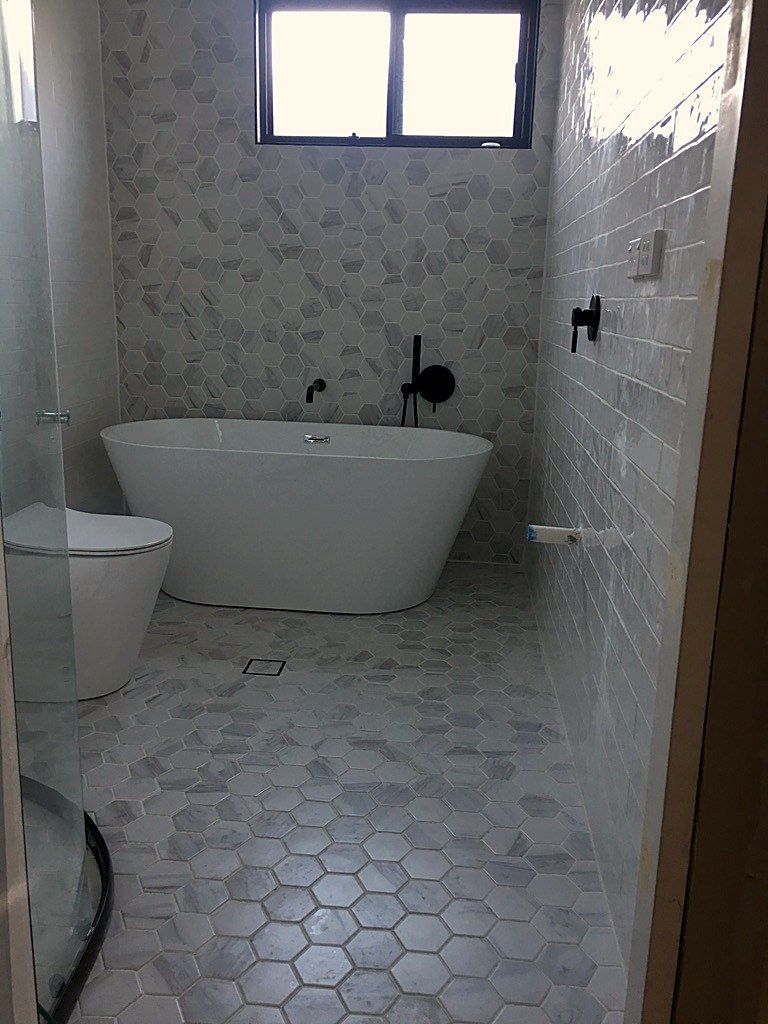 Freestanding bath and pebble floor tiling viewed head-on in this Sydney bathroom.