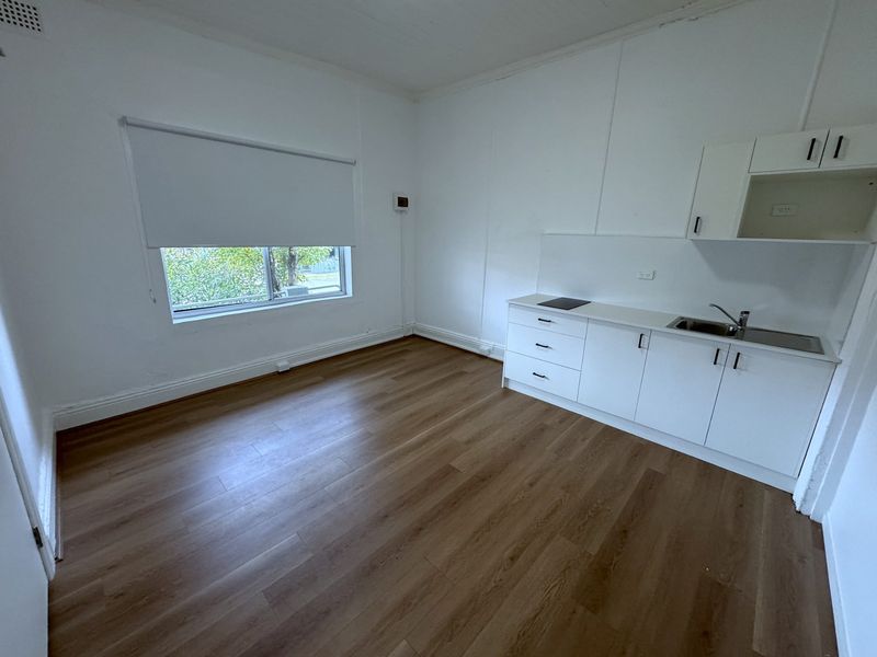 Empty room refurbished with a kitchenette bench, window and timber floorboards