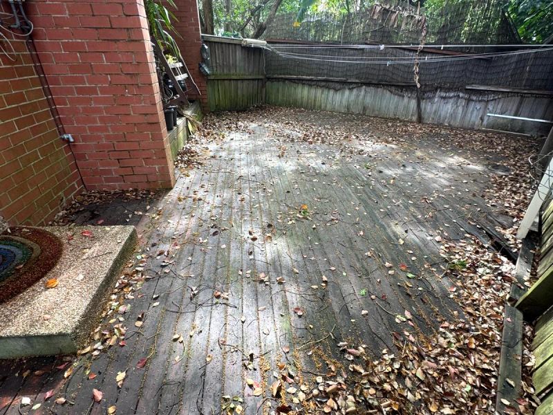 Before: the full courtyard deck, greyed and covered in leaves