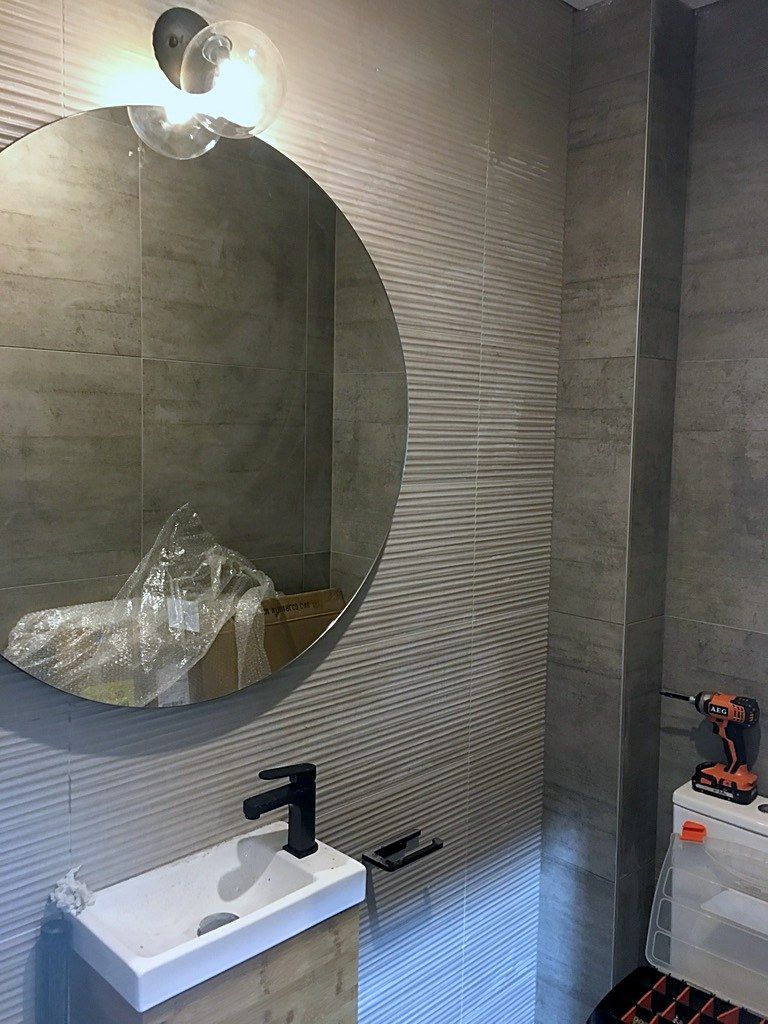 Round mirror and black tapware finish this bathroom.
