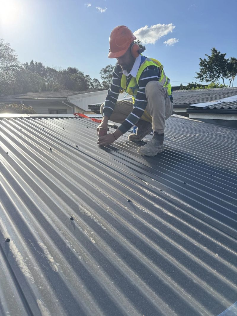 Tradesperson fixing new roof sheeting on a Sydney house.