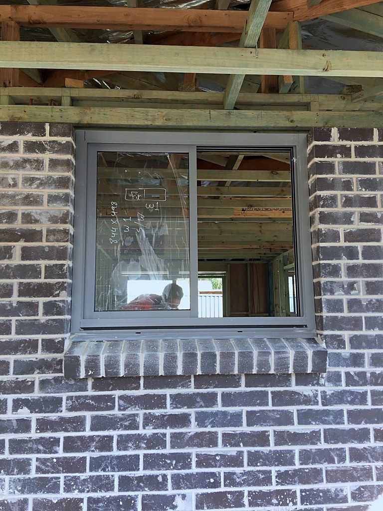 Timber roof framing rises above a brick window extension in Sydney.