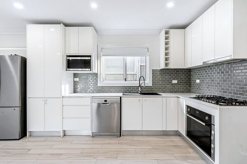 Renovated white kitchen with grey subway tile splashback and stainless appliances