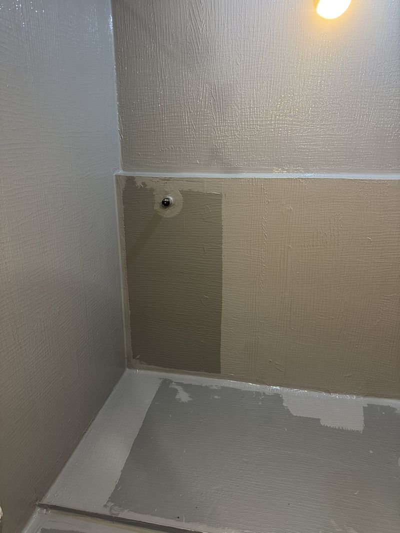 Grey waterproofing membrane coating the full height of the shower walls