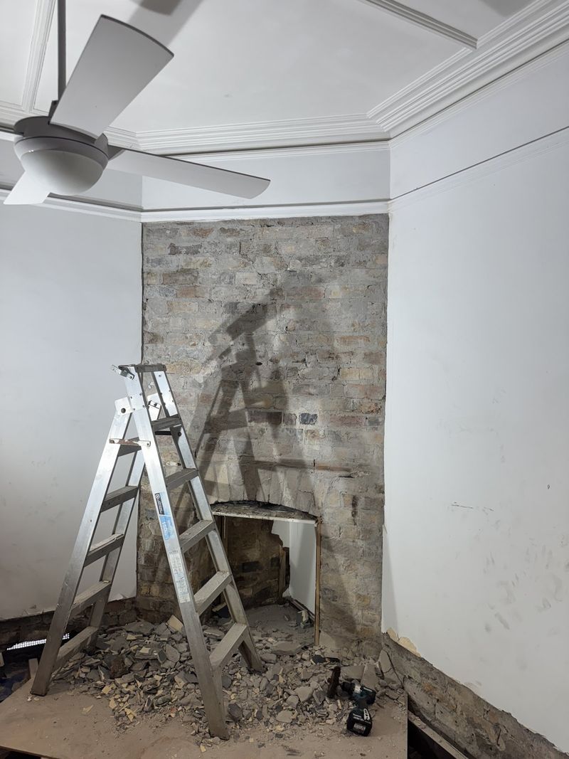 Fireplace opened back to bare brick with rubble still on the floor