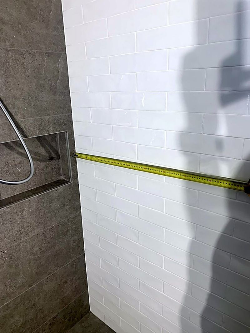 Tiled shower being measured against the specified dimensions