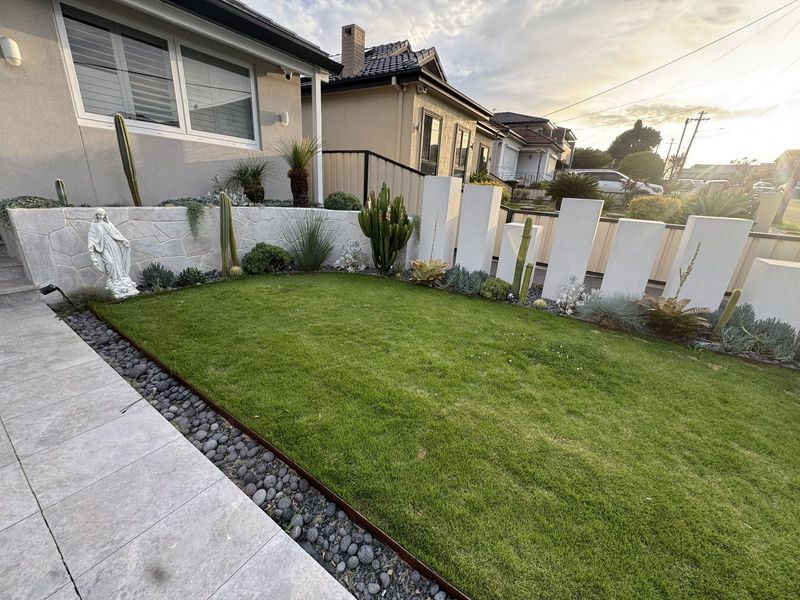 Rendered house frontage with a level lawn, pebble border and rendered screen walls