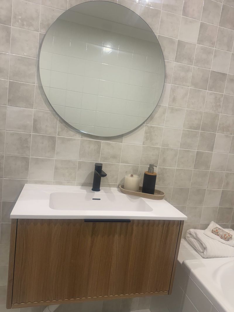 Black tapware and a timber vanity finish this bathroom's round-mirror feature wall.