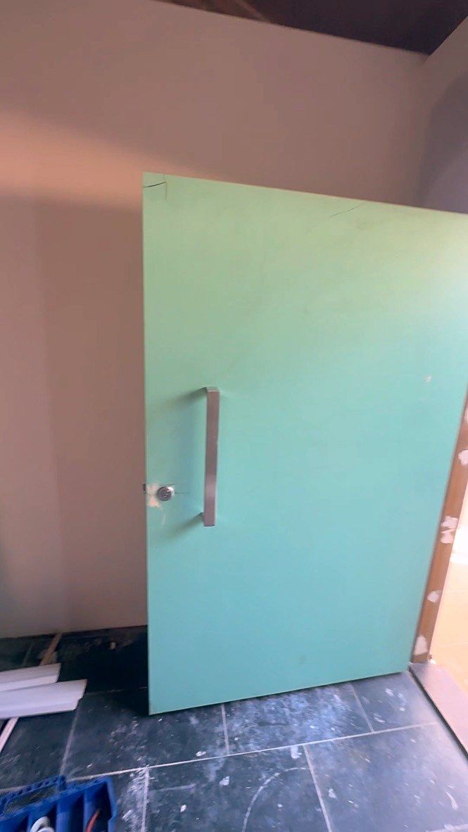 New door being fitted into place on a tiled floor.