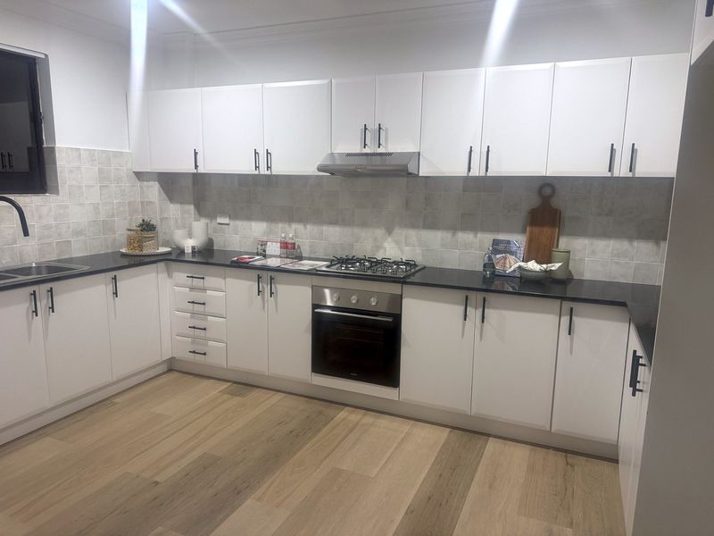 White kitchen renovation in Sydney with tiled splashback and floorboards