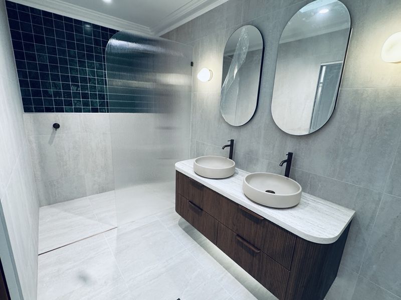 Twin vessel sinks and a curbless navy mosaic shower furnish this Sydney bathroom